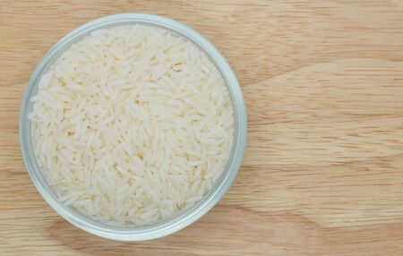 Thai  jasmine rice on glass bowl white wooden background, top viewの写真素材
