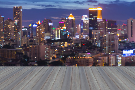 Opening wooden floor with abstract blurred bokeh Bangkok city lights during twilightの写真素材