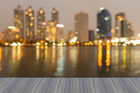 Opening wooden floor, night blurred light office building water front, abstract backgroundの写真素材
