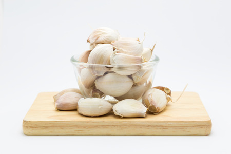 Glass cup rood garlic on wooden board, on white backgroundの写真素材