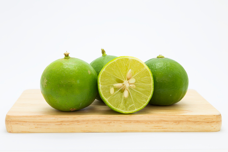 Wooden board with fresh limes on white backgroundの写真素材