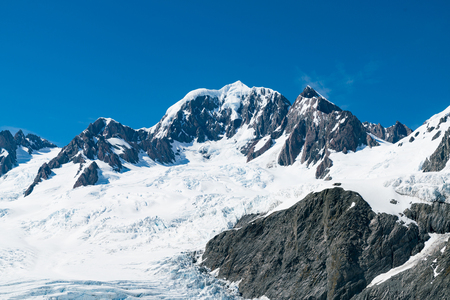 New Zealand black volcano mountain with snow covered with clear blue sky background, natural landsape の写真素材