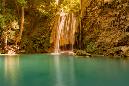Green water lake with waterfall in tropical deep forest, natural landscape backgroundの写真素材