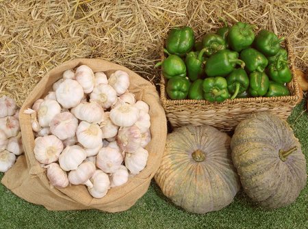 Bell pepper, garlic, pumpkin for sale on straw backgroundの写真素材