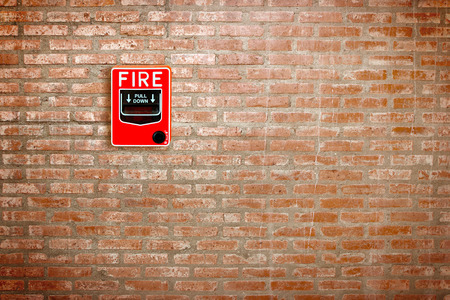 fire break glass alarm switch on brick wall background