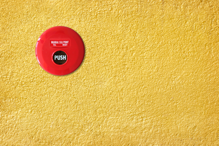 fire break glass alarm switch on the yellow cement wall texture.