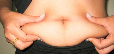 Fat belly pull the hand out. It makes bad health obesity.の写真素材