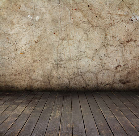 Abandoned aged grunge cement wall and brown wooden floorの写真素材
