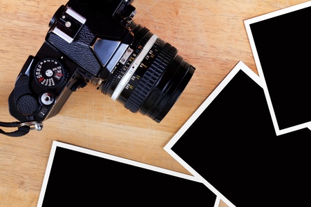Old film camera and photo paper on wooden table
