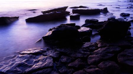 Purple blue color of sunset on rock coast seascapeの写真素材