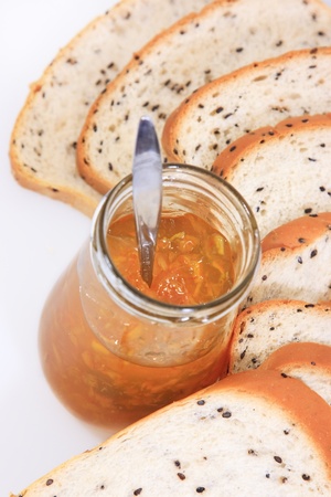 Spread slice brown wholewheat bread and orange jam on white backgroundの写真素材