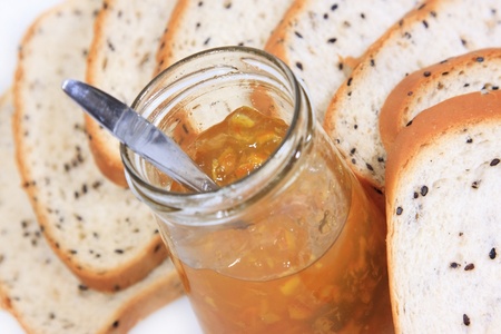 Spread slice brown wholewheat bread and orange jam on white backgroundの写真素材