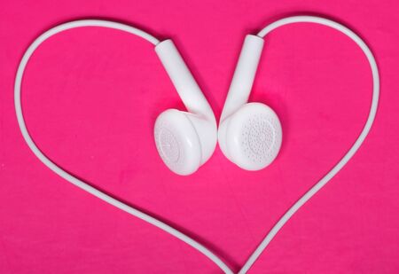 White earphone on pink background look like heart shapeの写真素材