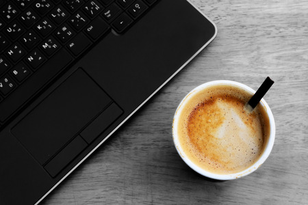 Hot latte paper cup with computer notebookの写真素材