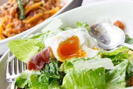 Eating Caesar salad with soft boiled eggの写真素材