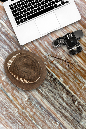 Computer notebook camera and hat on wooden deskの写真素材