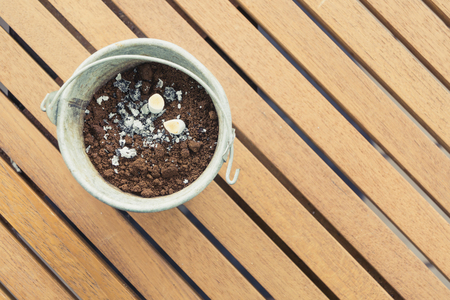 smoked cigarette in metal bucket ashtray on wooden tableの写真素材