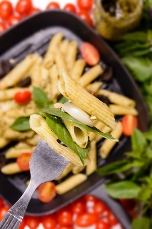 Penne pesto sauce pasta with grape tometo and black oliveの写真素材