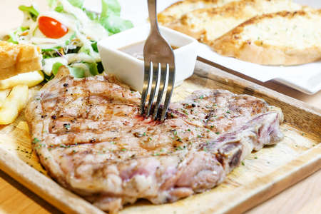 Medium rare tbone beef steak on wooden plateの写真素材
