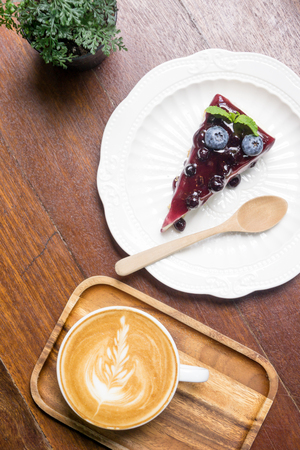 Blue berry cheese cake and coffee latte on wooden deskの写真素材