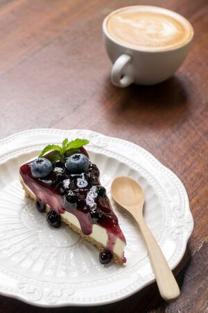 Blue berry cheese cake and coffee latte on wooden deskの写真素材