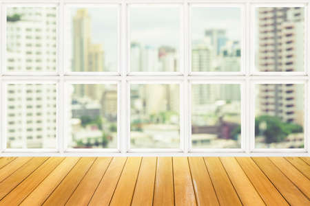 Wooden table beside white window with city viewの写真素材