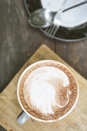 Hot coffee latte art cup on grunge old wooden table with copy spaceの写真素材