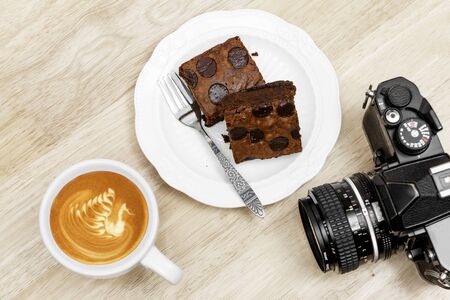 Chocolate brownie coffee latte break and vintage camera on wooden tableの写真素材