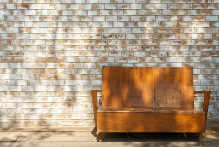 Shadow light on vintage ooden couch with white orange brick wall background textureの写真素材
