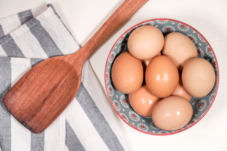 Eggs in bowl and wooden turner utensilの写真素材