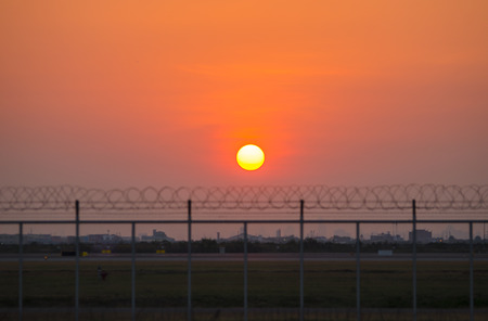 Silhouette of barbed wire over sunset sky, abstract backgroundの写真素材