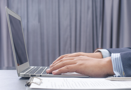 business, education, people and technology concept - close up of male hands with laptop computer, notebook and pen taking notesの写真素材