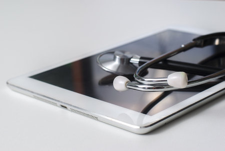 medical stethoscope on modern digital tablet pc in laboratory on wood table. Concept of medical or research themeの写真素材