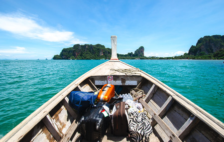 Travel background: wooden boat sailing on transparent blue sea against mountains and blue skyの写真素材