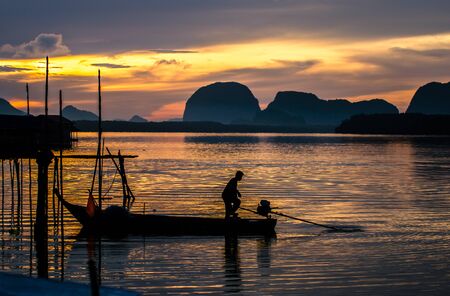 Fishing boat in the golden morning light.Fishermen fishing in the early morning golden light. The life of a fisherman. Fishermen on the river.Photo Fisherman Silhouette.Fisherman boatの写真素材