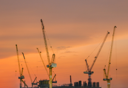 Abstract Industrial background with construction cranes silhouettes over amazing sunset skyの写真素材