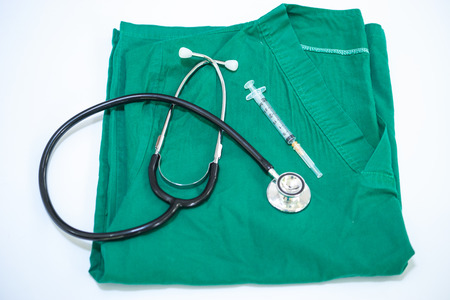 Stethoscope with blue doctor coat on wooden table with shallow DOF evenly matched and backgroundの写真素材