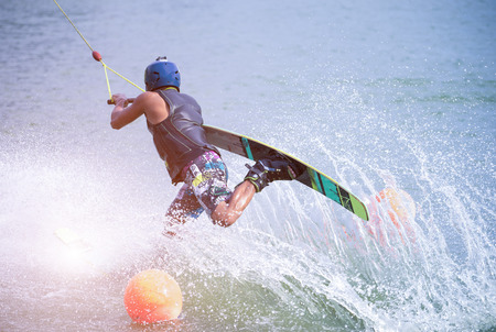 Wakeboarder making tricks on the sea. Wakeboarding. Water sports on the beach.の写真素材