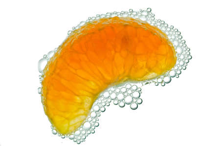 Ripe orange covered with bubbles in water isolated on a white background.の写真素材