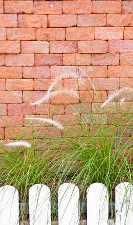 Orange brick wall beside the wooden fence.の写真素材