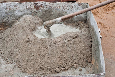 Construction worker mixing concrete with a hand mixer