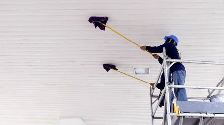 Selective focus at 2 workers on scaffolding using flat wet mops to cleaning white ceiling of petrol station, occupation concept, low angle view copy spaceの写真素材