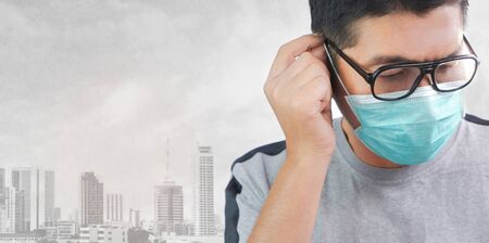 Close up Asian man in eyeglasses with gray t-shirt wearing protective mask and blurred dusty...