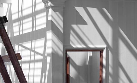 Sunlight and shadow of scaffolding with roof structure on surface of wooden door frame in white...