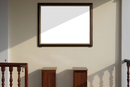 Sunlight and shadow on surface of vintage blank photo frame on mastic yellow cement wall with part of 2 wooden stands and balustrade in warm tone style, interior architecture conceptの写真素材