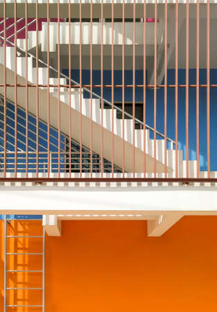 Fire escape with protective balusters outside of blue and orange facade in vertical frameの写真素材