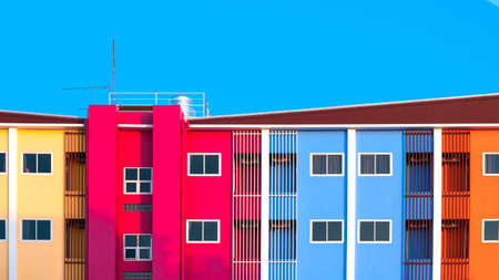 Glass windows and safety baluster on high section of colorful building against blue sky backgroundの写真素材