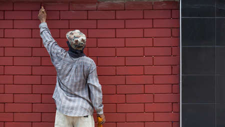 Rear view of Asian worker is painting to renovate the old block wall outside of house buildingの写真素材