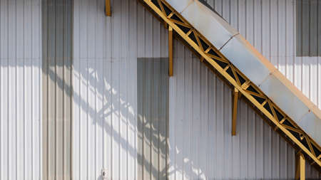 Part of the old yellow conveyor line on metal sheet wall of warehouse building