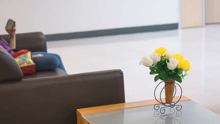 Focus at vintage artificial flowers vase on the table with blurred background of child using...